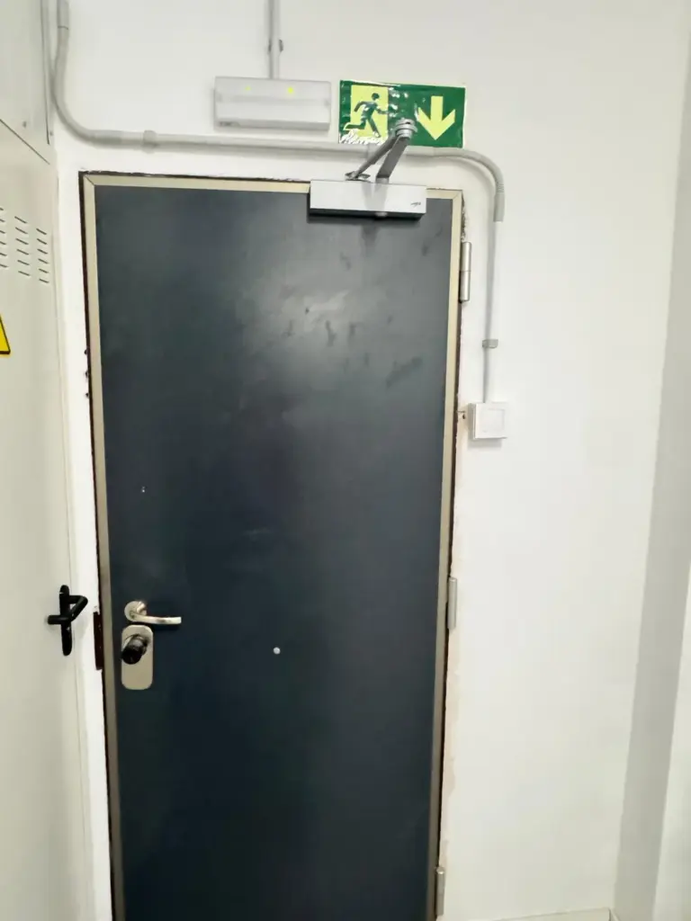 Puerta metálica con cierrapuertas en salida de emergencia